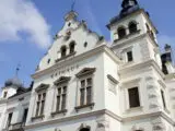 White Rathaus (town hall) façade with decorative gables, arched windows, and a tall tower against a blue sky, European architectural detail
